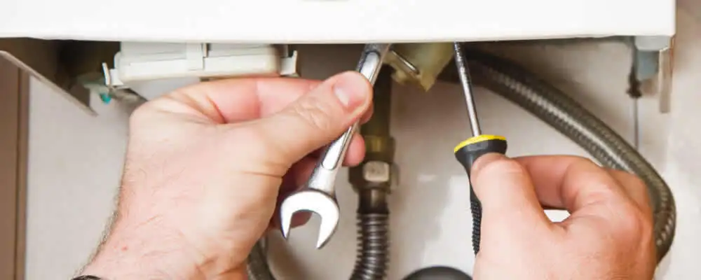 Boiler repair technician tightening pipe fittings and connections in Redmond, WA