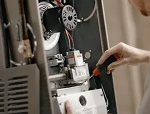 Furnace repair technician inspecting internal components and wiring in Redmond, WA