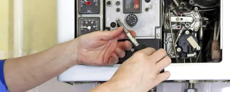 Heating repair technician adjusting boiler controls and components in Redmond, WA