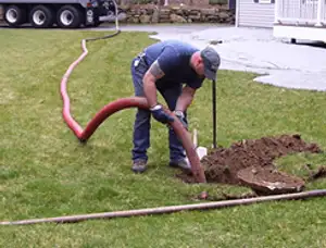 Septic pumping technician servicing a residential septic tank with a vacuum hose in Redmond, WA