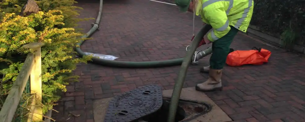 Septic tank cleaning technician servicing a septic tank with a vacuum hose in Redmond, WA