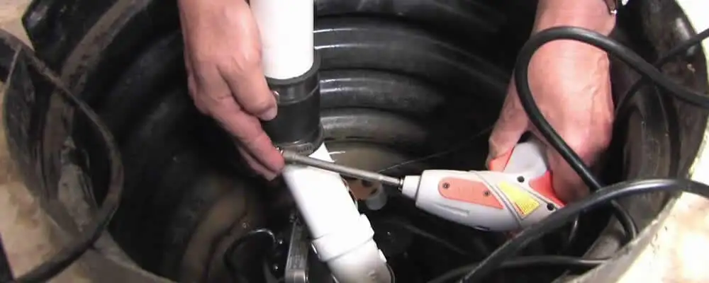 Sump pump installation technician connecting PVC discharge piping in Redmond, WA