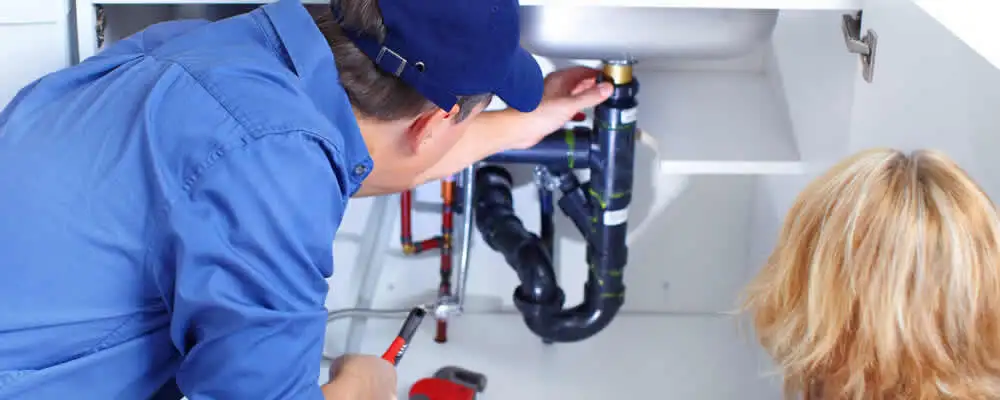 Plumber repairing under-sink drain pipes and fittings in Redmond, WA