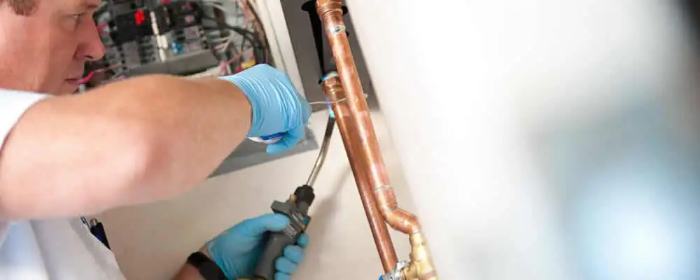 Water heater repair technician testing copper pipe connections and controls in Redmond, WA